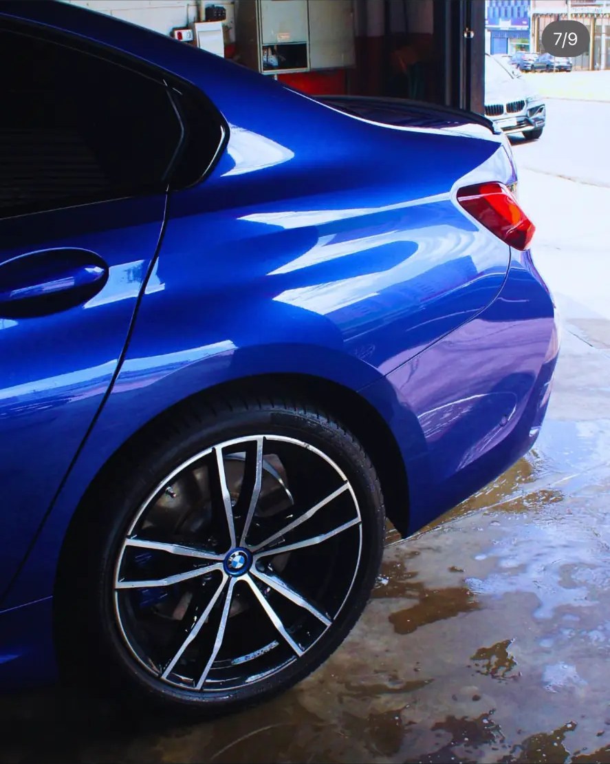 Lateral traseira e roda do BMW azul após funilaria e pintura